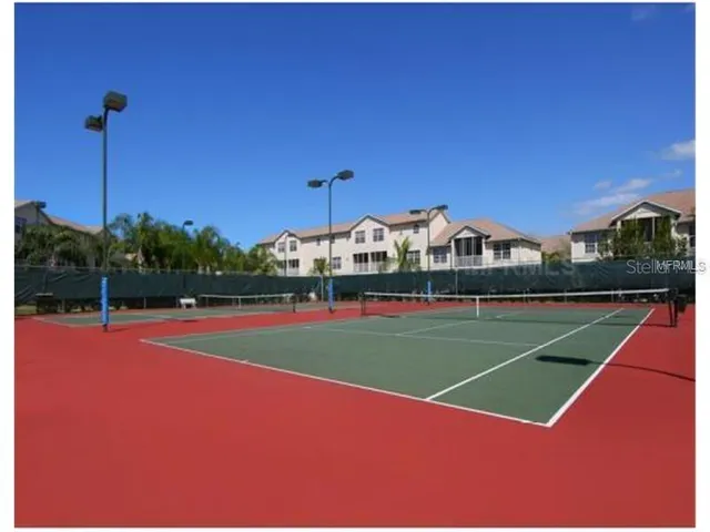 a view of a tennis ground with large trees