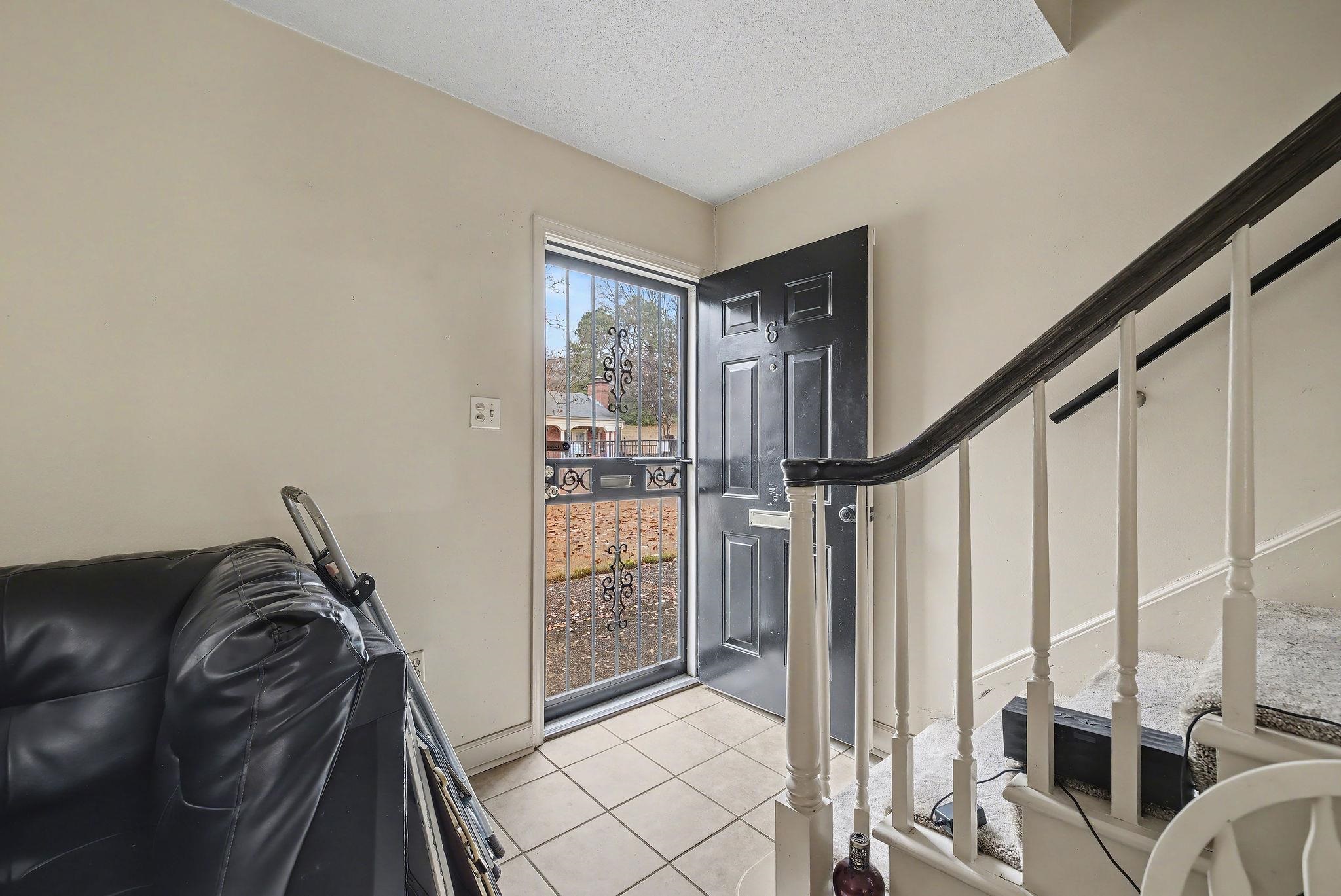 Foyer entrance with light tile patterned floors and stairs