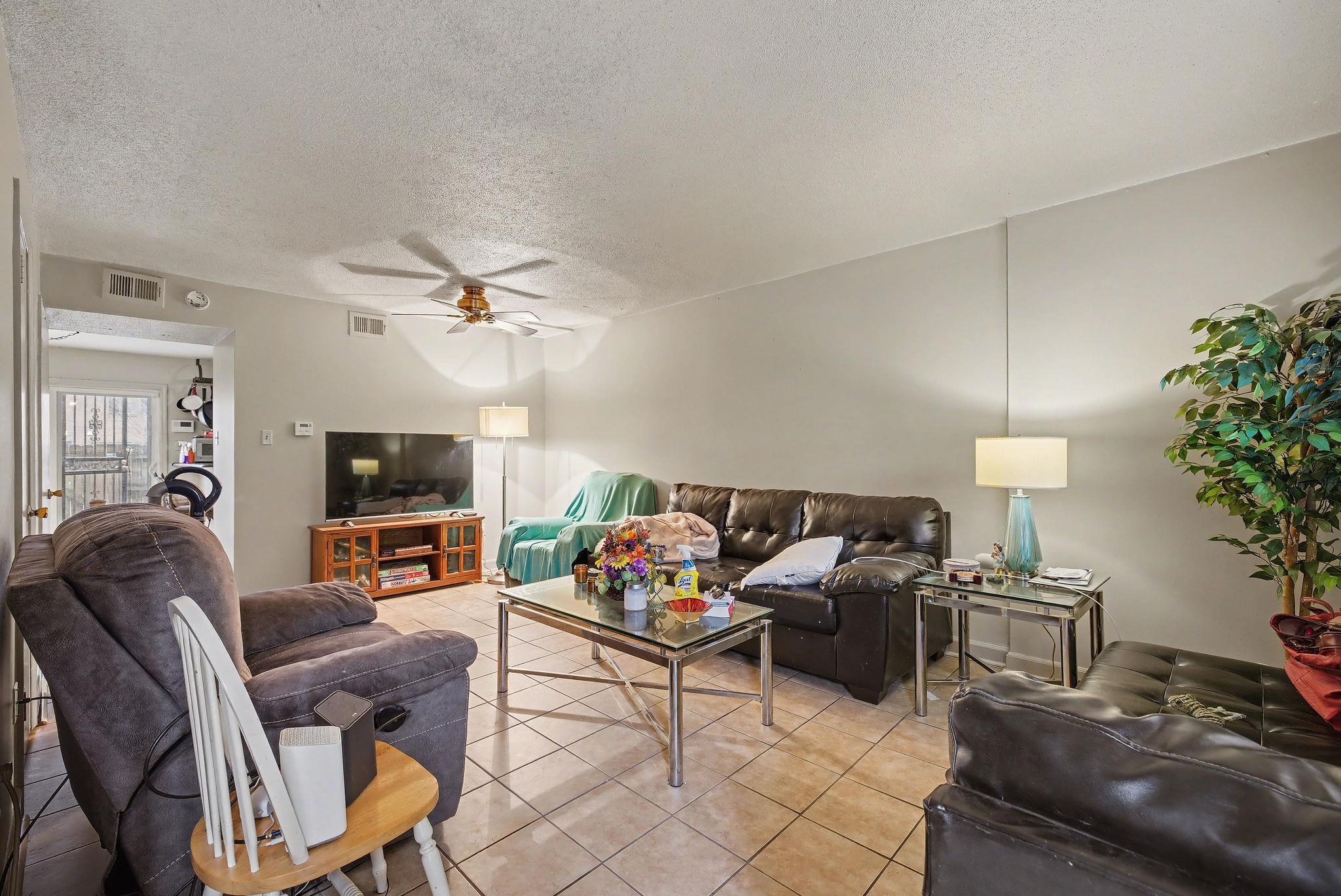 Tiled living area with a textured ceiling and ceiling fan