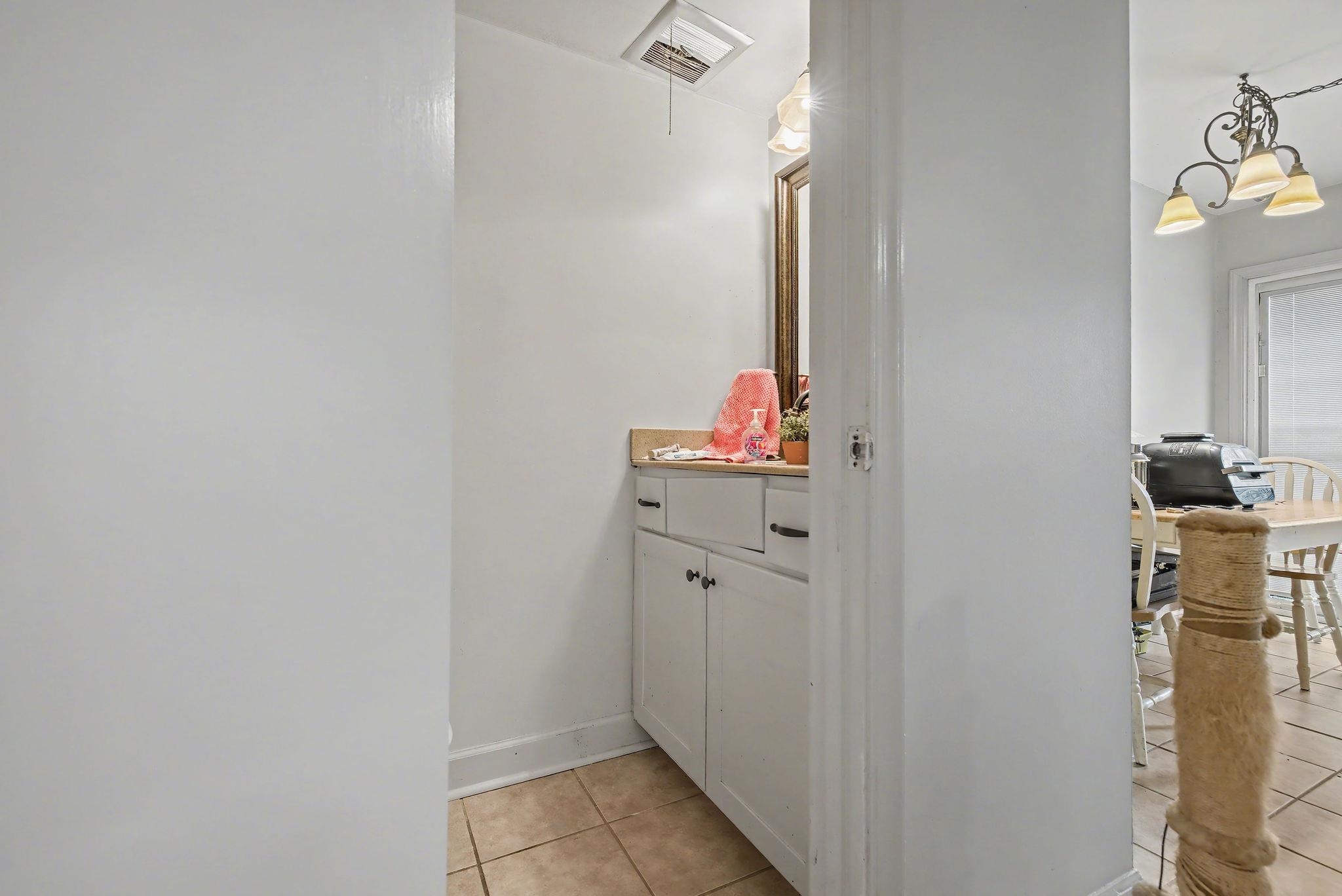 Half bathroom featuring light tile patterned floors, vanity, and a chandelier