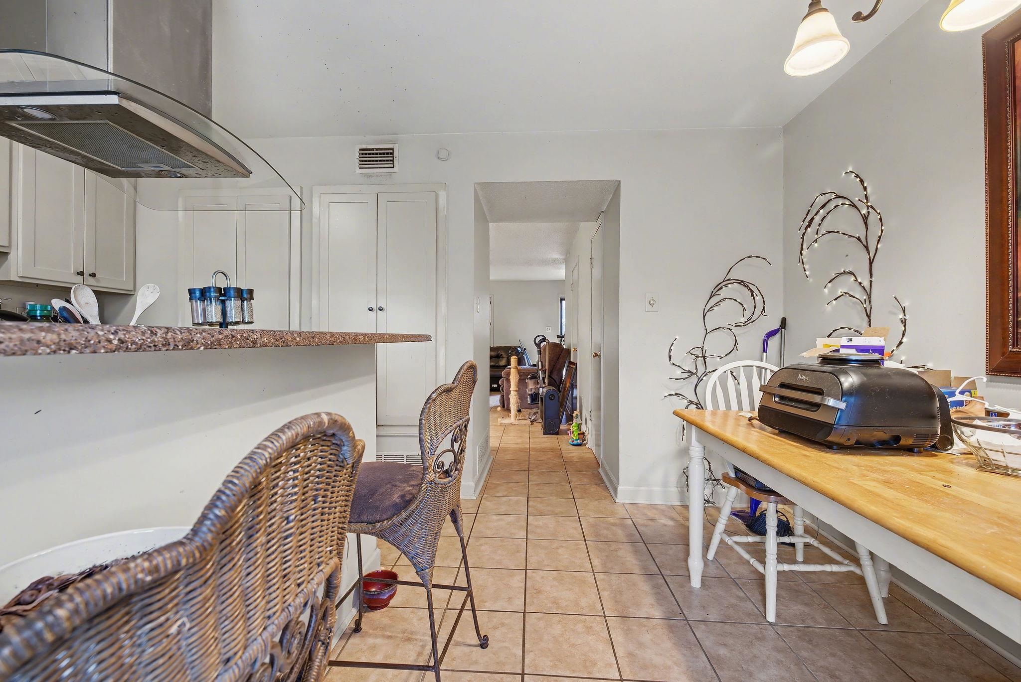 5700 Quince Road, Unit 6 Memphis, TN 38119 - Photo 8 of 15 Kitchen featuring exhaust hood, white cabinetry, light tile patterned floors, and a breakfast bar