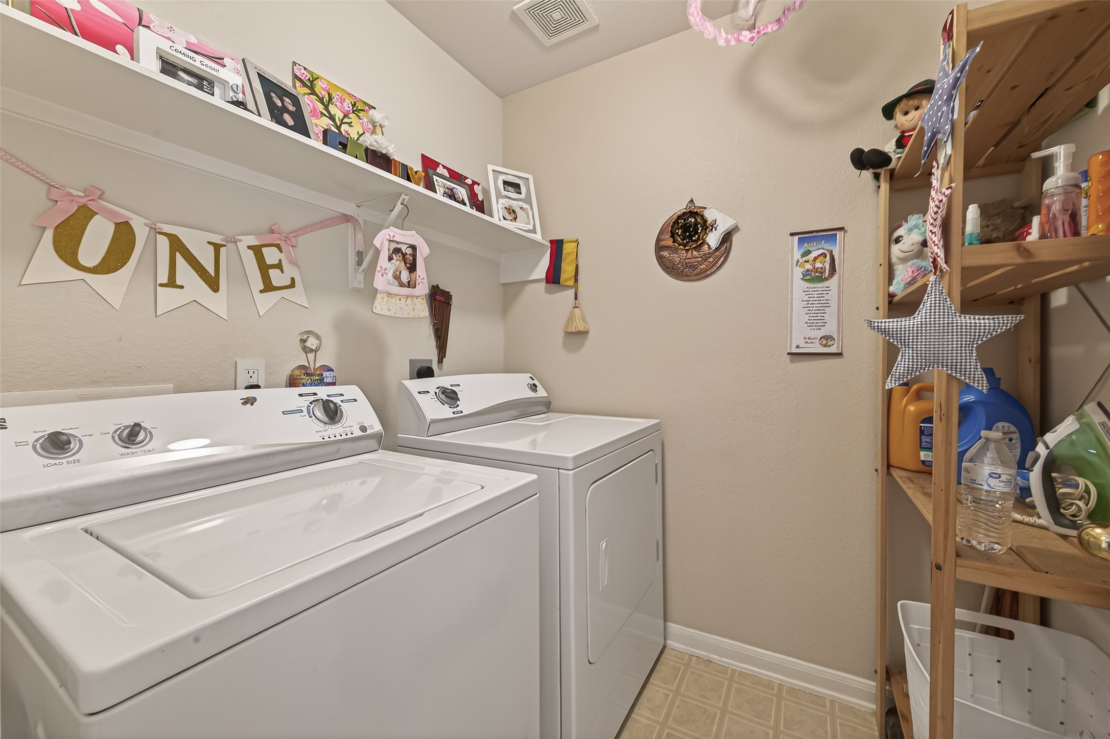 9902 Victoria Point Lane Houston, TX 77075 - Photo 12 of 35 This cozy laundry room features a washer and dryer set, wall shelving for storage, and a wooden rack for additional organization. The space is decorated with charming personal touches, creating a welcoming atmosphere.