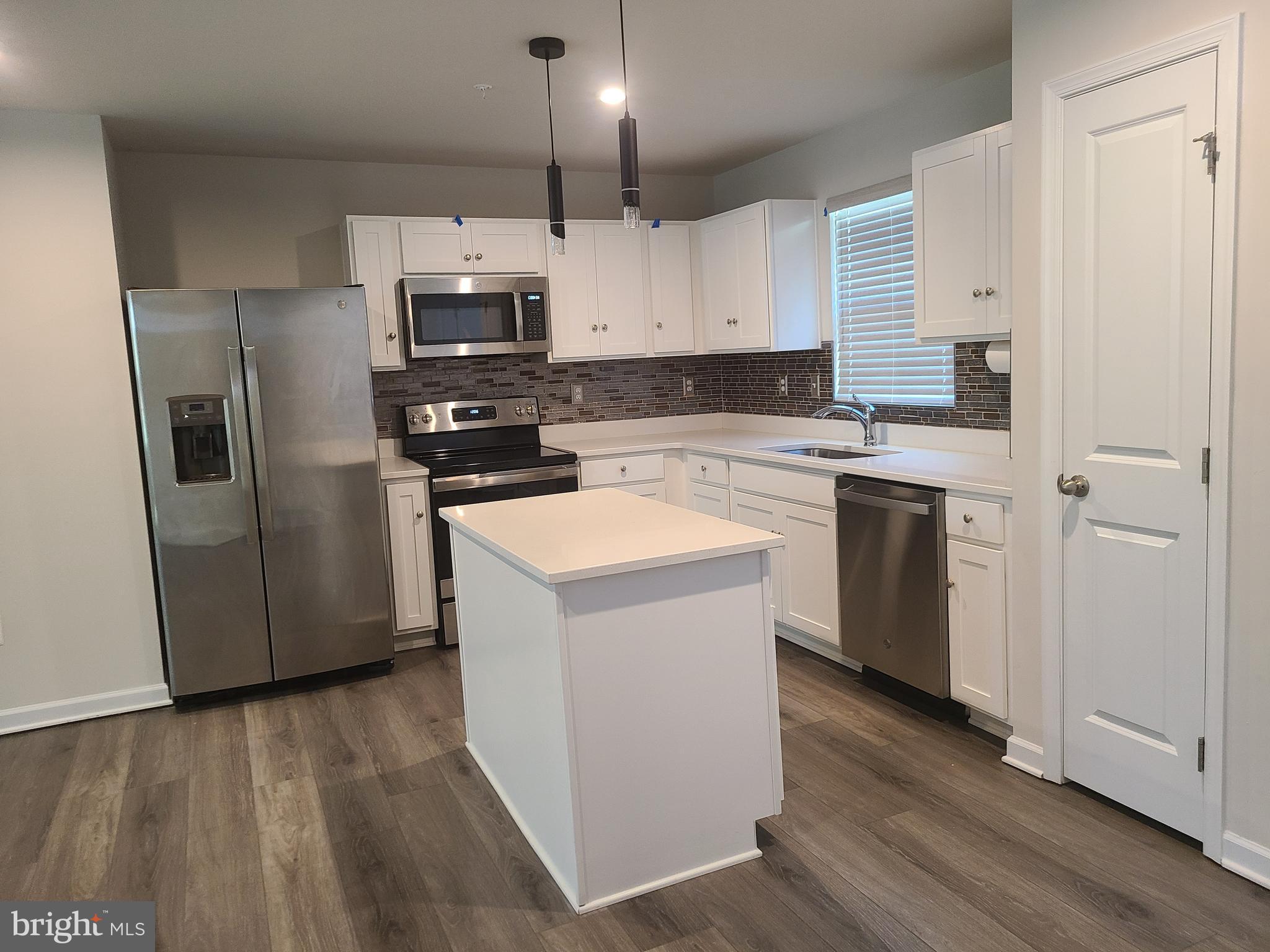 105 Mariners Way Cambridge, MD 21613 - Photo 3 of 45 a kitchen with stainless steel appliances a refrigerator a stove a microwave and wooden floor