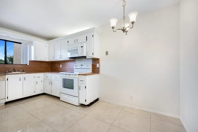 a kitchen with white cabinets a sink dishwasher and a stove with wooden floor