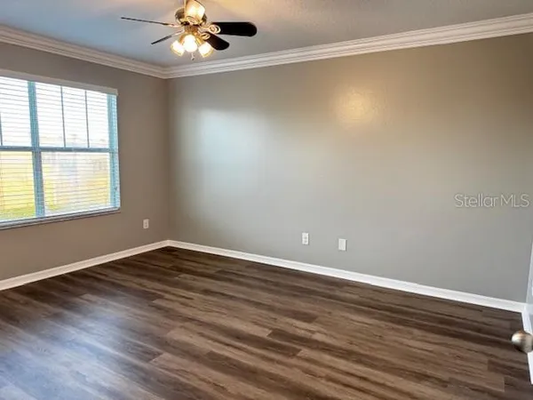 a view of an empty room with wooden floor and a window