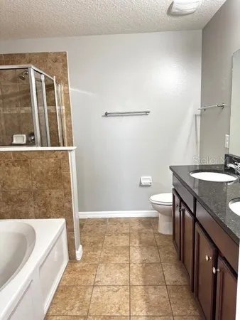 a bathroom with a granite countertop sink a toilet a bathtub and shower