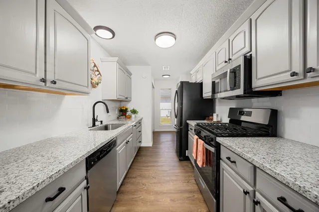 a kitchen with stainless steel appliances granite countertop a sink stove and refrigerator
