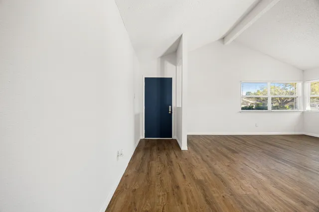 a view of a big room with wooden floor and windows