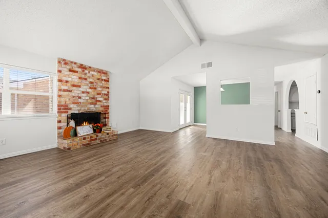 a view of a livingroom with wooden floor and a fireplace