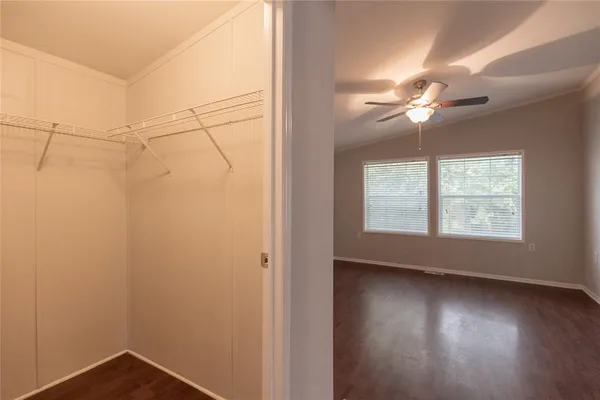 an empty room with wooden floor fan and windows