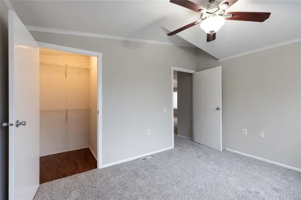 an empty room with closet and a chandelier fan