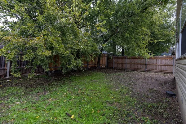 a view of backyard with green space and wooden fence
