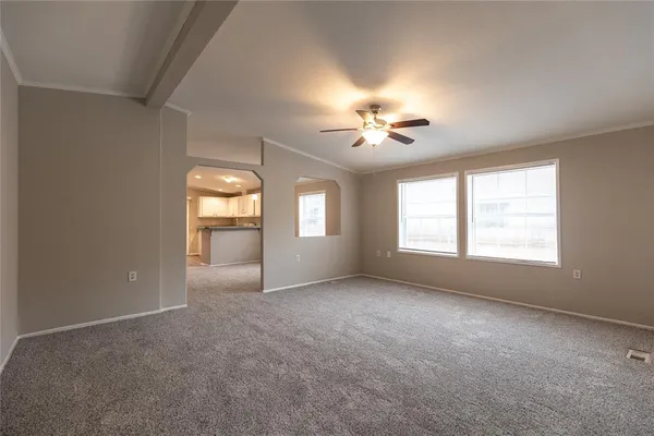 an empty room with chandelier fan and windows