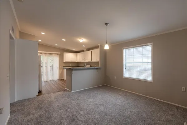 a view of an empty room with windows & cabinet