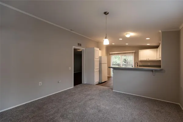 a view of an empty room with window and chandelier
