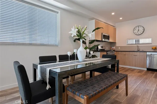 a living room with stainless steel appliances kitchen island a table chairs in it and wooden floors