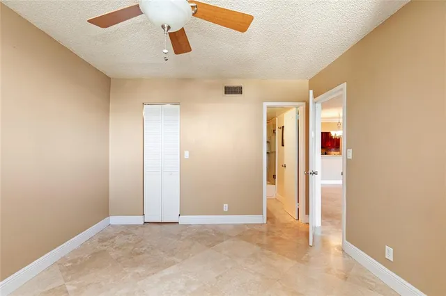 an empty room with closet and a chandelier fan