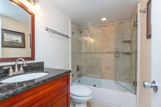 a bathroom with a granite countertop sink toilet and shower