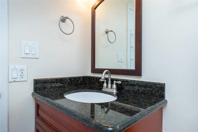 a bathroom with a granite countertop sink and a mirror