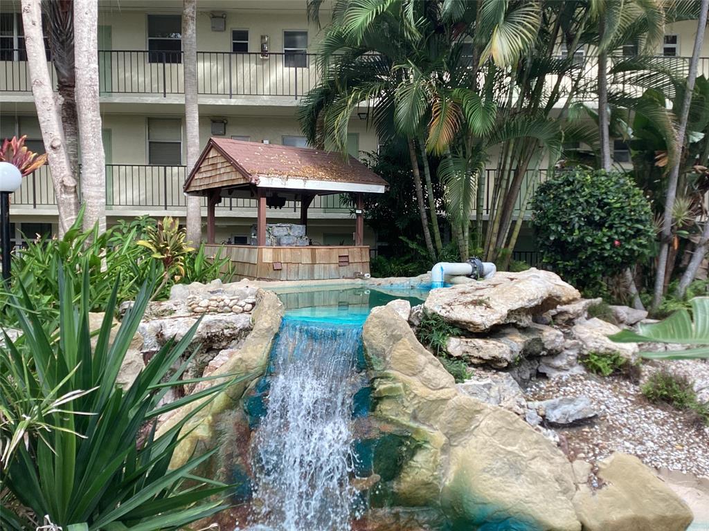 5300 Northeast 24th Terrace, Unit 416C Fort Lauderdale, FL 33308 - Photo 18 of 26 a backyard of a house with table and chairs under an umbrella