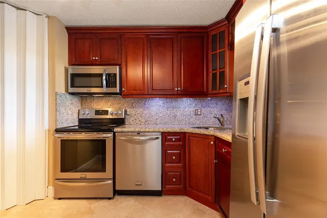 a kitchen with stainless steel appliances granite countertop a stove a microwave and a refrigerator