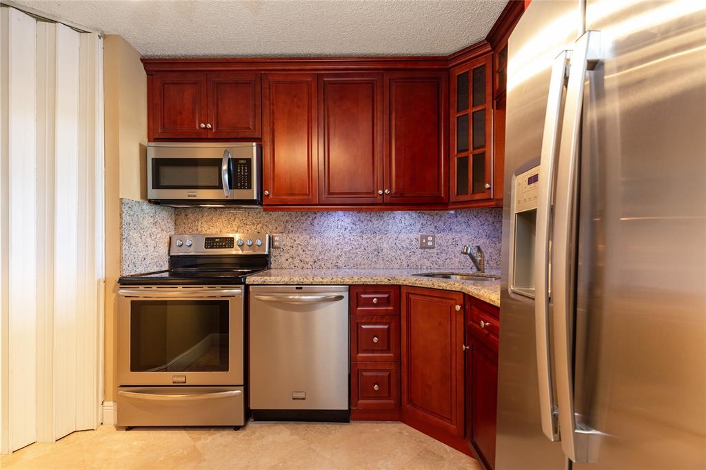 5300 Northeast 24th Terrace, Unit 416C Fort Lauderdale, FL 33308 - Photo 5 of 26 a kitchen with stainless steel appliances granite countertop a stove a microwave and a refrigerator