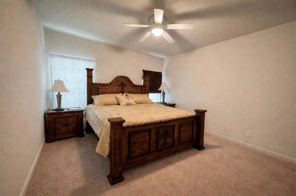 121 Rey Del Mar Circle Weatherford, TX 76085 - Photo 16 of 29 a bedroom with a bed and a chandelier