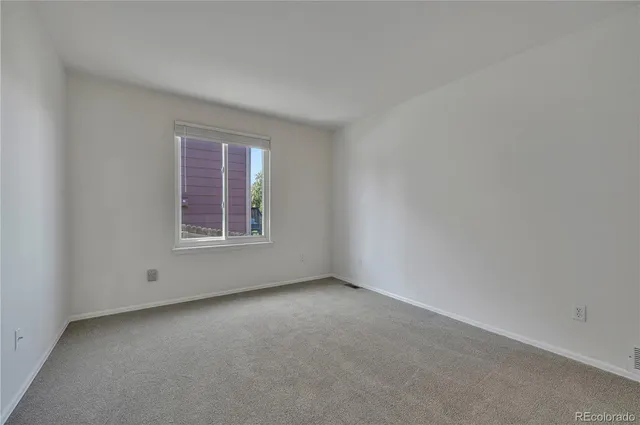 a view of empty room with wooden floor and kitchen