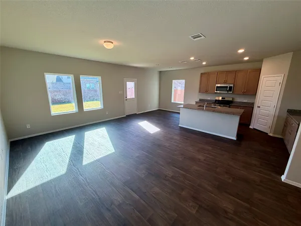 a living room with stainless steel appliances furniture and a wooden floor