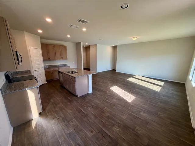 a kitchen with kitchen island wooden floors appliances and cabinets