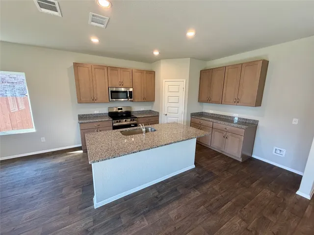 a kitchen with stainless steel appliances granite countertop a stove a sink and a refrigerator