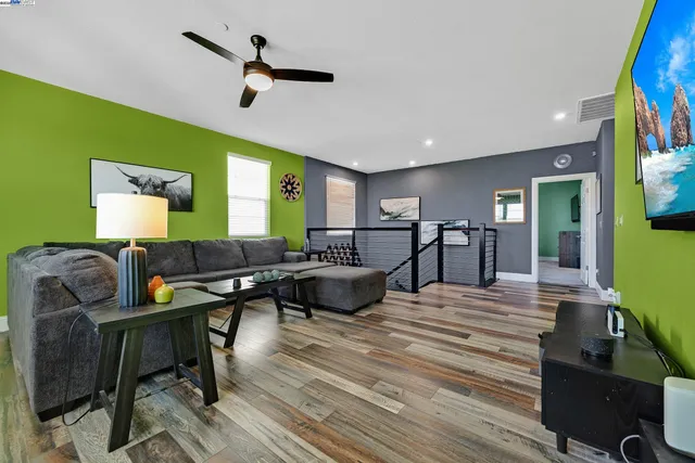 a living room with furniture kitchen view and a wooden floor