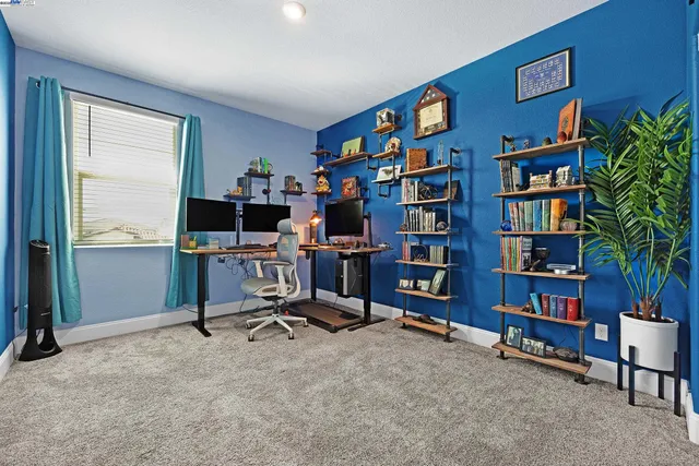 a view of a workspace with bookshelf and a window
