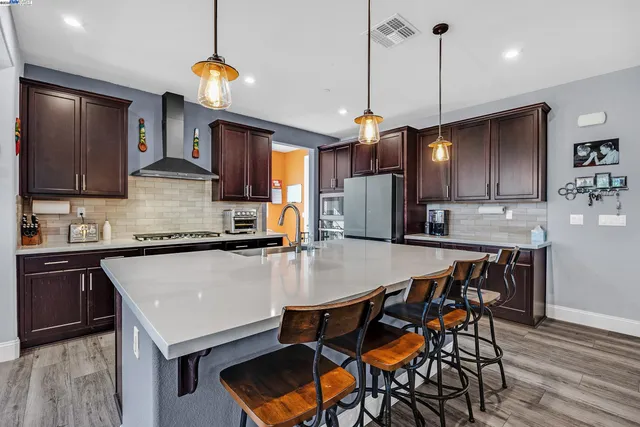 a kitchen with stainless steel appliances granite countertop a stove a refrigerator a sink a stove and island with wooden floor