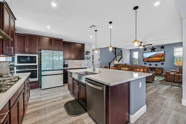 a kitchen with kitchen island a stove a counter space a sink and a wooden floor