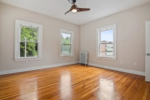 a view of an empty room with window and wooden floor