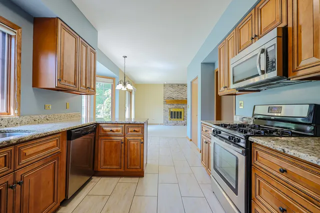 a kitchen with stainless steel appliances granite countertop a stove a sink and a microwave