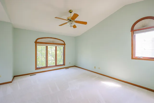 an empty room with windows and fan