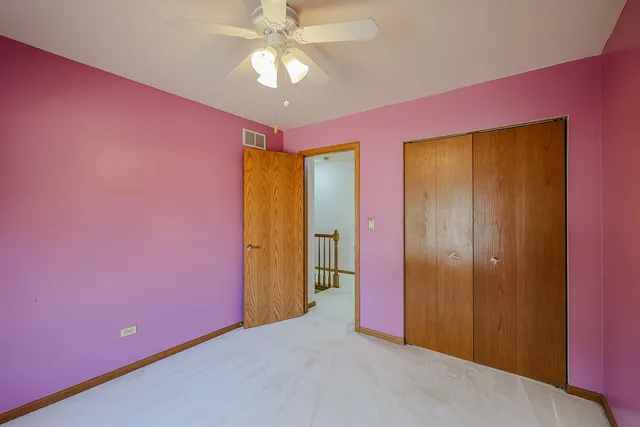 an empty room with a chandelier fan and a glass door