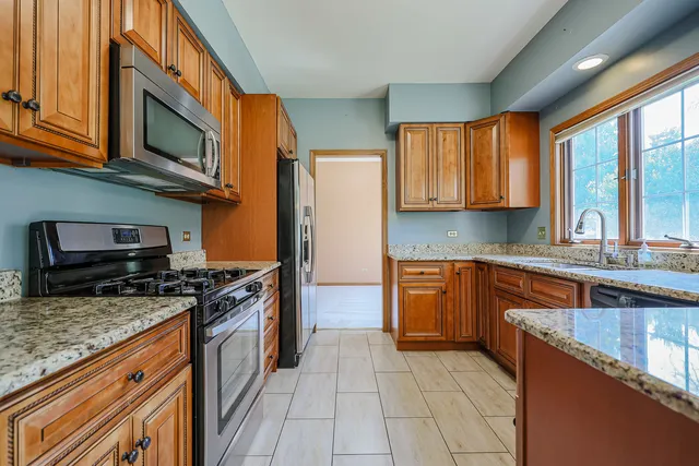 a kitchen with stainless steel appliances granite countertop a stove top oven a sink dishwasher a refrigerator and a microwave oven