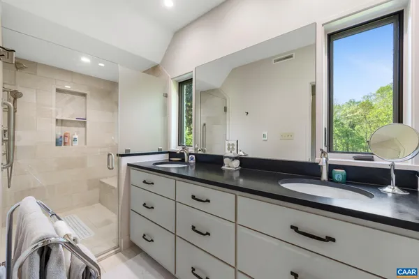 a bathroom with a granite countertop double vanity sink a mirror and a bathtub