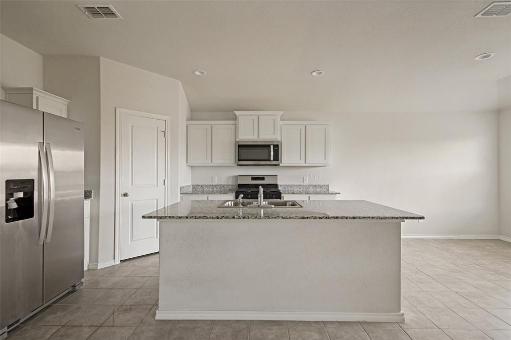 621 Spaulding Street Justin, TX 76247 - Photo 10 of 22 a kitchen with stainless steel appliances granite countertop a sink and a refrigerator