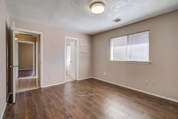 an empty room with wooden floor and windows
