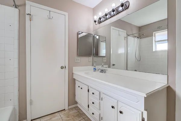a bathroom with a double vanity sink a large mirror and shower