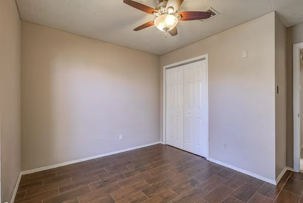 an empty room with wooden floor and chandelier fan