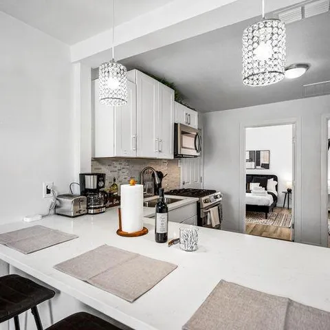 a kitchen with stainless steel appliances granite countertop a stove a sink a refrigerator a dining table and chairs with wooden floor