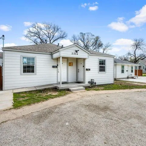 a view of a white house with a large space and large trees