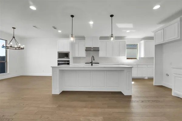a view of kitchen with stainless steel appliances refrigerator stove and wooden floor
