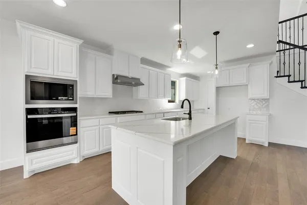 a kitchen with white cabinets and appliances