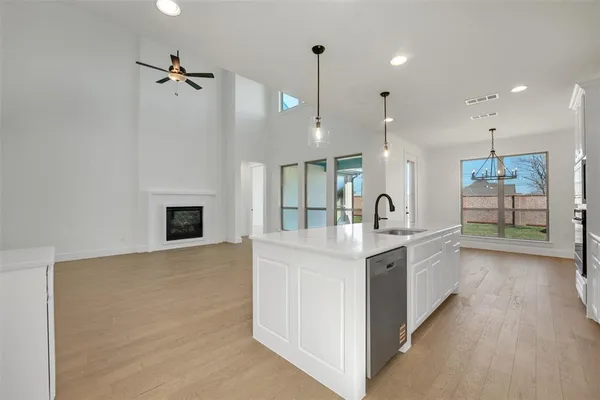 a large kitchen with a large counter top a sink stainless steel appliances and cabinets
